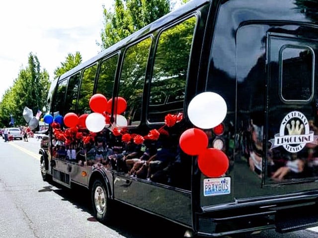 Northwest Limousine's party bus with red white and blue balloons, taking part in a parade.