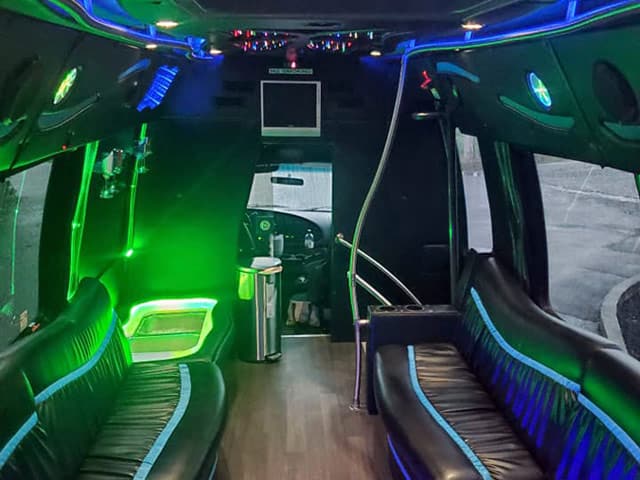 Interior view of the party bus with seating on either side, lights and a screen at the front